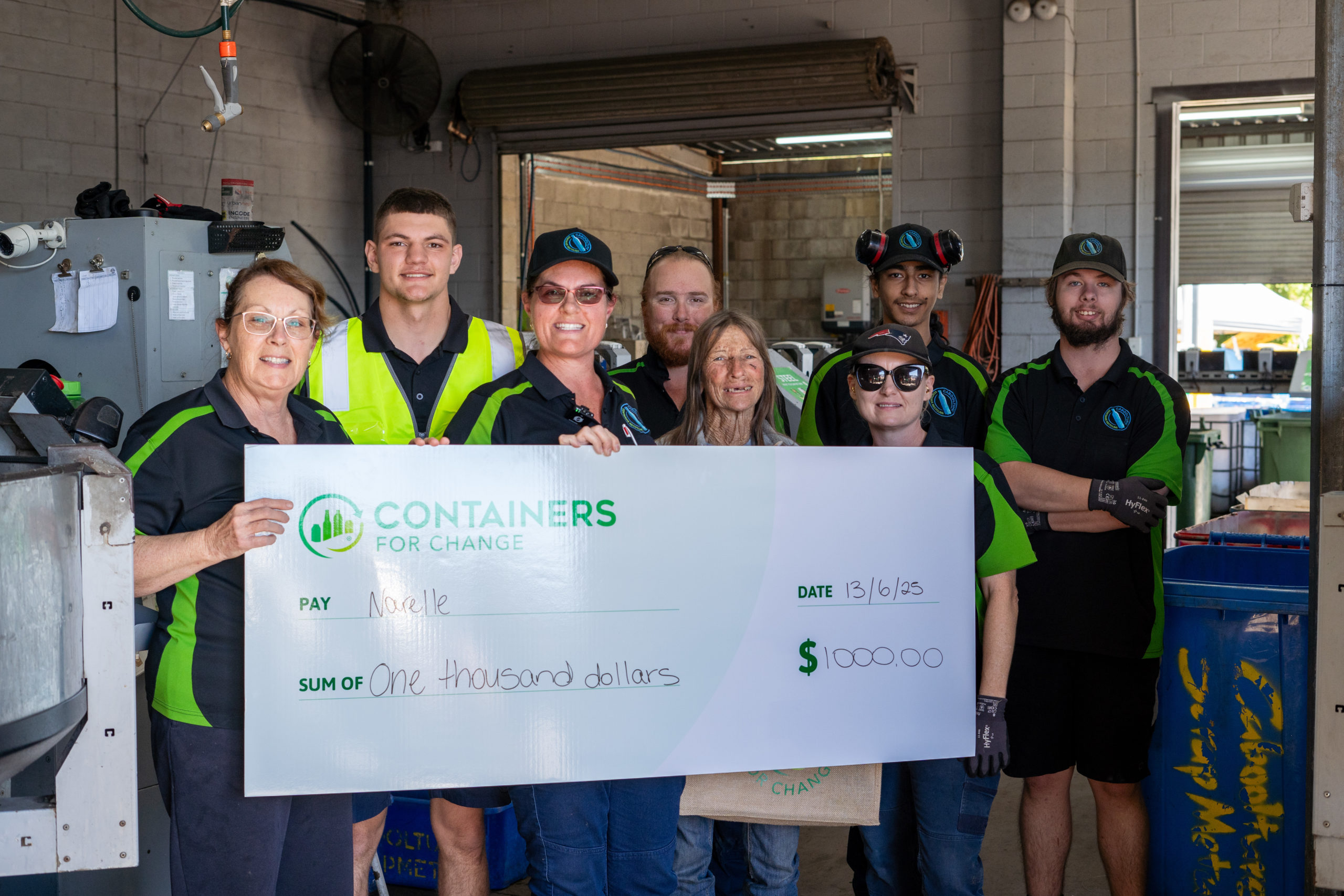 A group of people stand behind a large novelty cheque.
