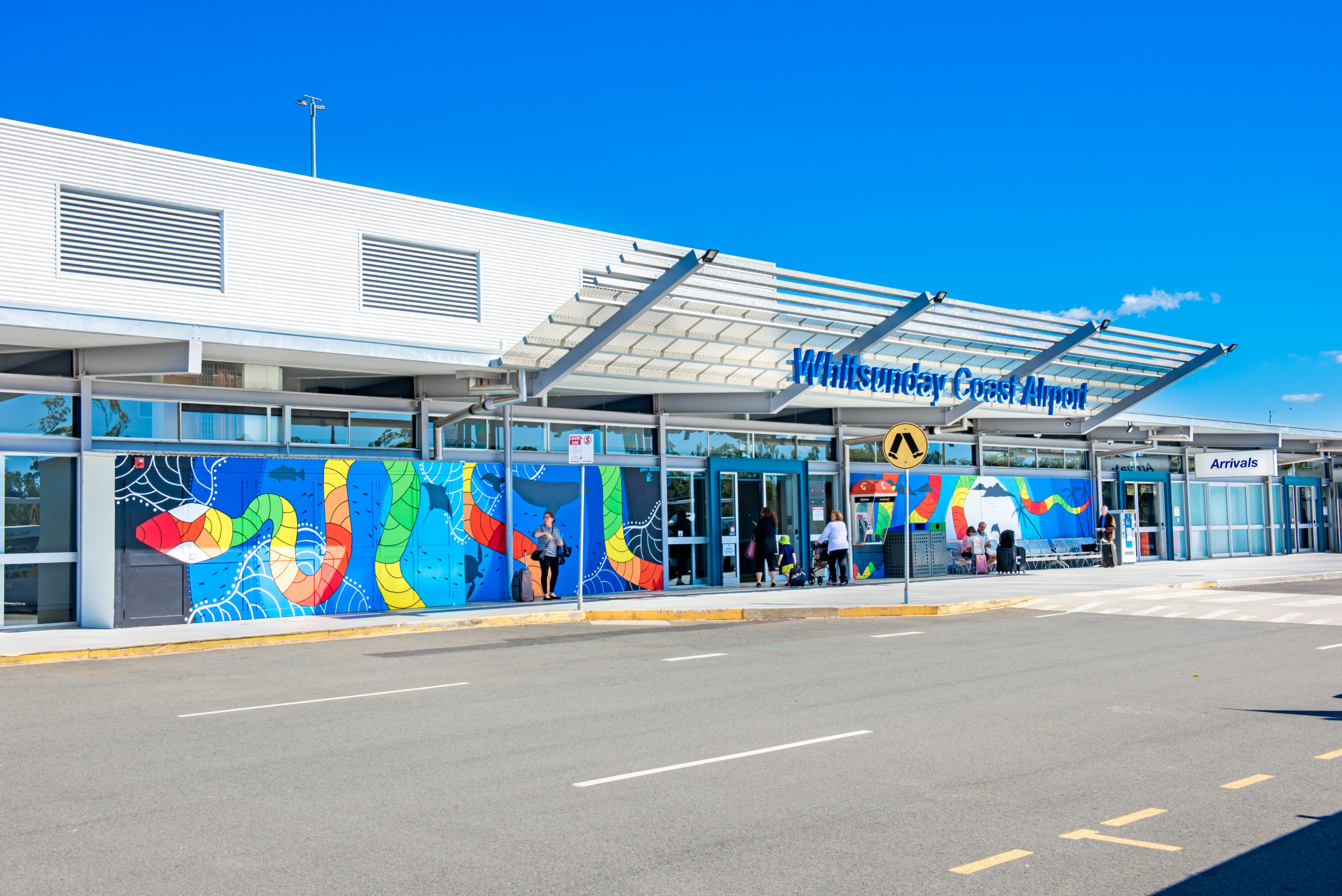 The entrance to an airport against a blue sky.