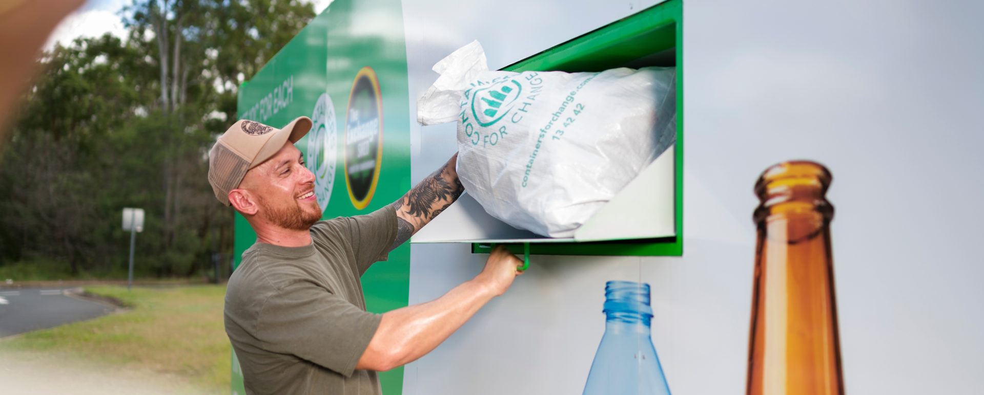 A man puts a large white bag into the shute of a large shipping container.