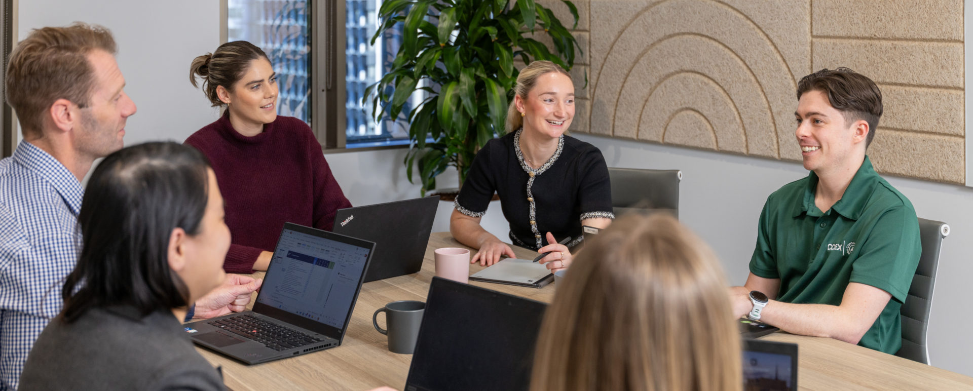 A group of people sit at a table in an office.