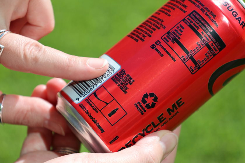 A finger pointing to the 10c refund mark on a drink can.
