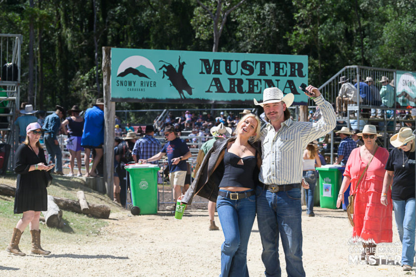 People walking past the Muster Arena entrance with green recycling bins positioned nearby.