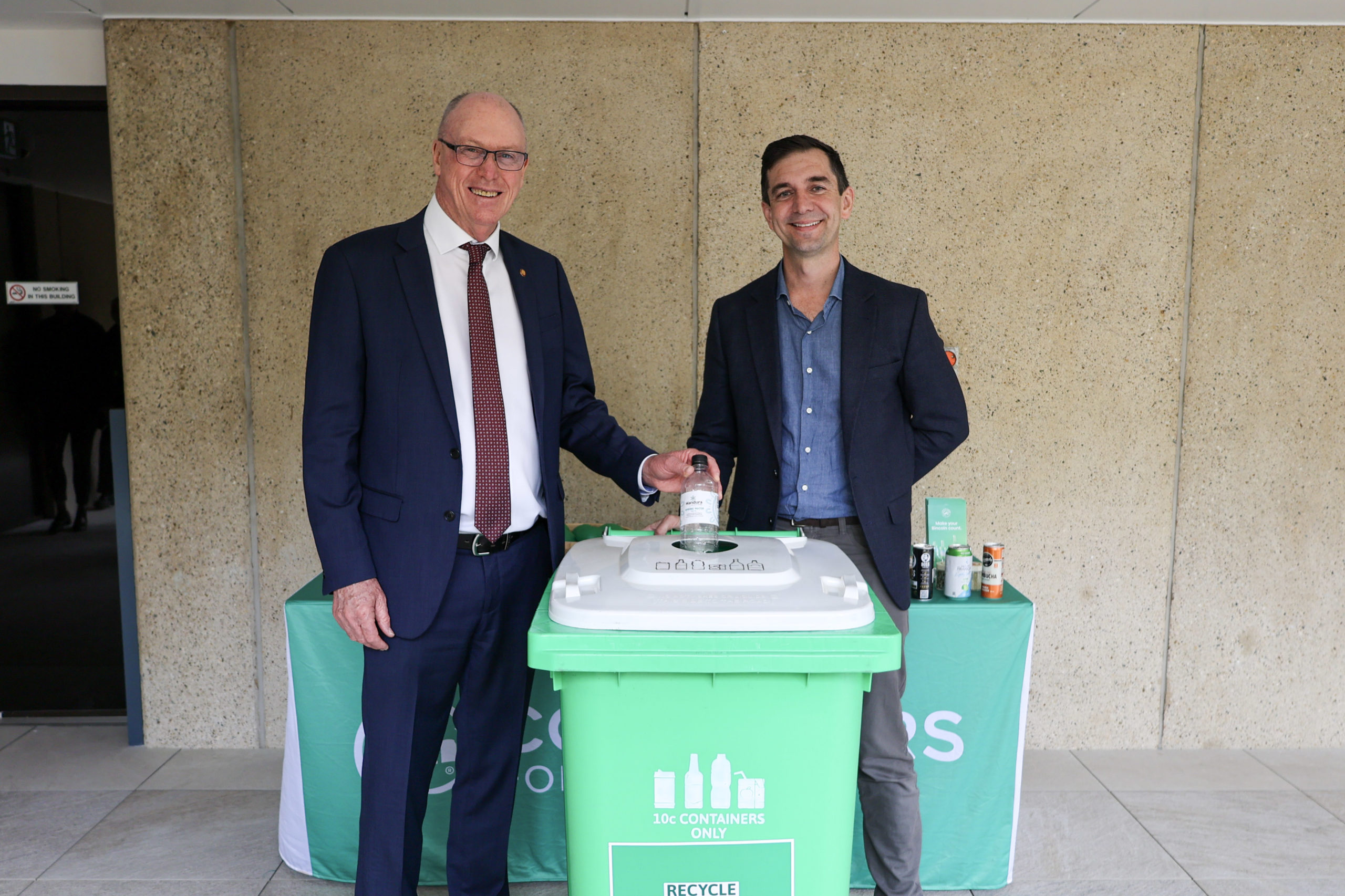 Hon Pat Weir MP and COEX CEO Trevor Evans stand beside a Containers for Change collection bin at Queensland Parliament.