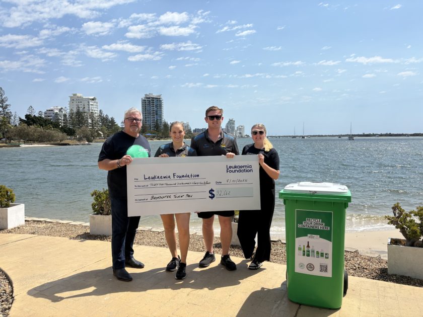 Four people holding a Leukaemia Foundation donation cheque beside a green Containers for Change bin at Broadwater Tourist Park.