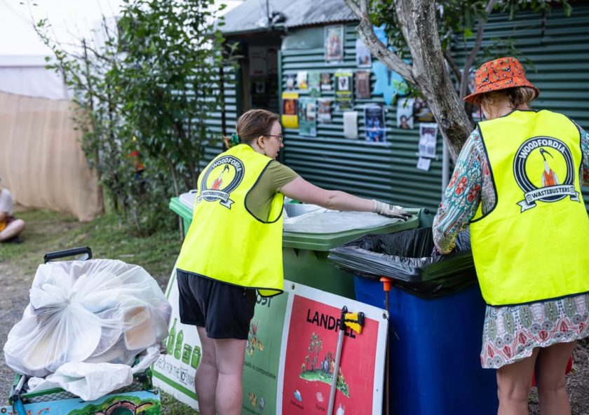 Two volunteers sorting recyclable materials into collection bins at Woodford Folk Festival.