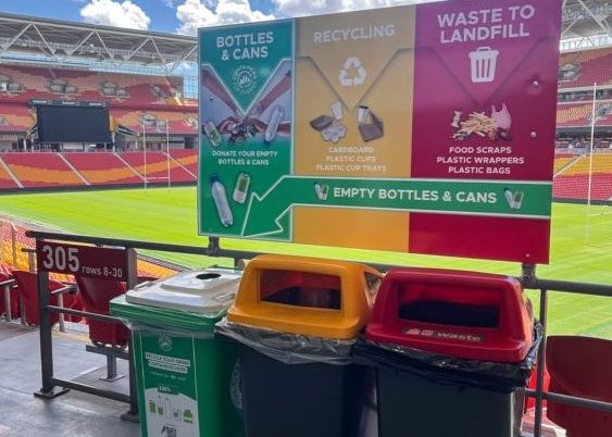 Three waste and recycling bins with coloured lids and sorting signage at Suncorp Stadium.